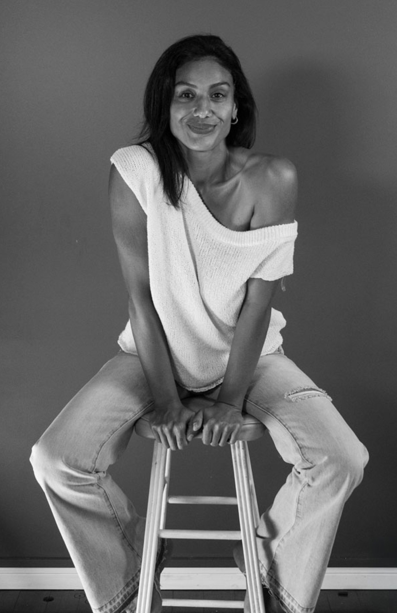 Giselle Kermanioun seated on a stool, smiling at the camera